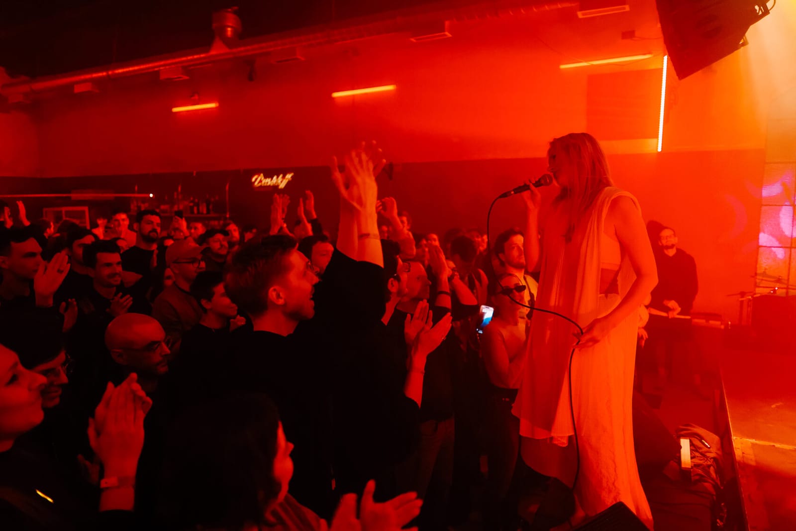 Вокалистка в белом платье поёт над толпой в красном свете клуба, Changeover Festival 2025, Белград