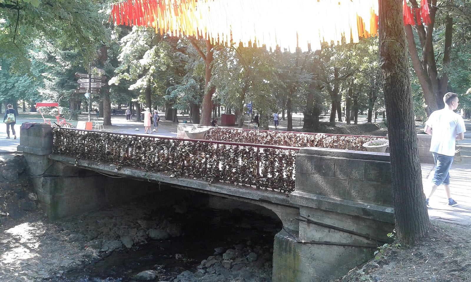 Мост любви в Врнячкой Бане: перила в замочках, над мостом гирлянды лент