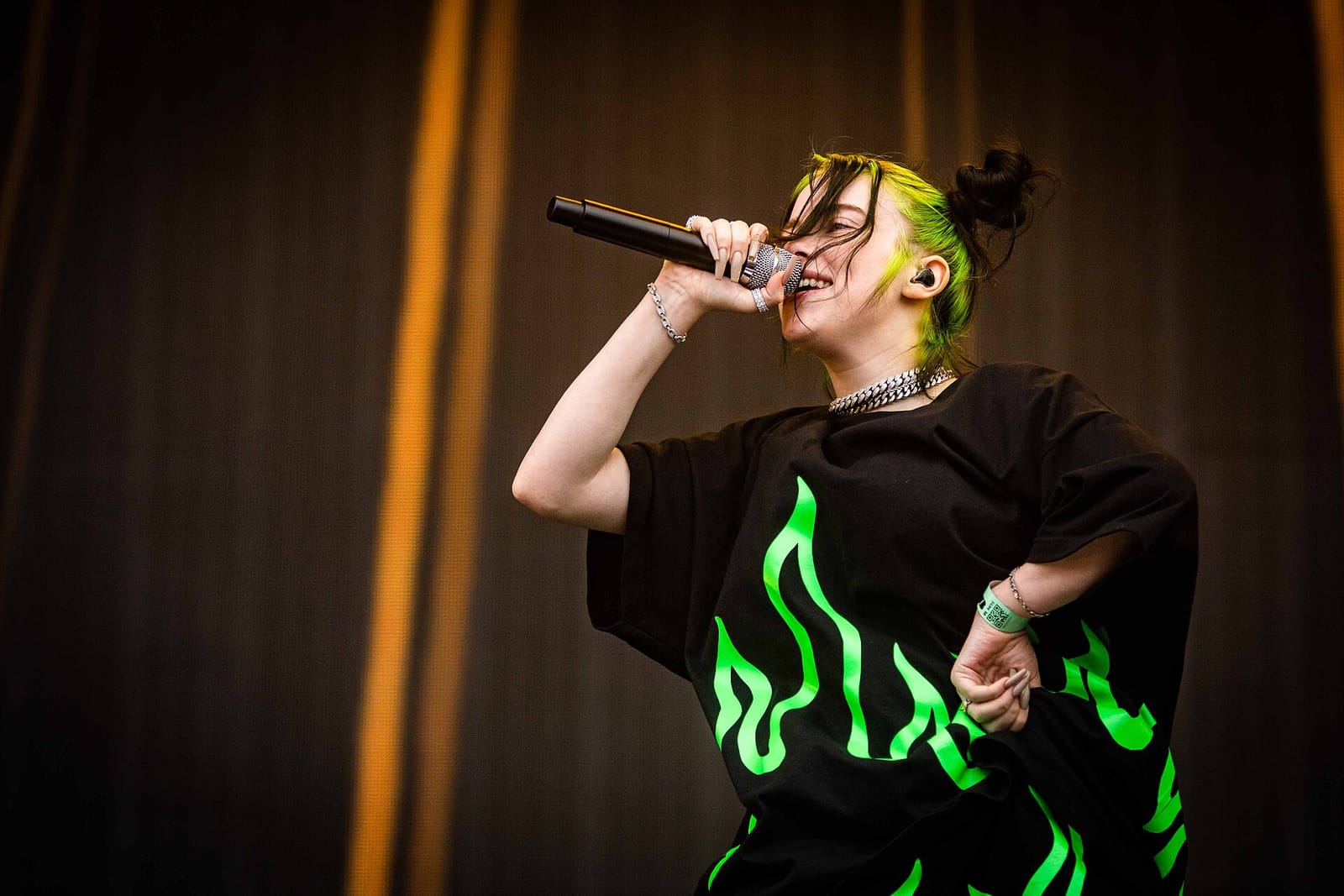 Билли Айлиш с микрофоном на сцене Pukkelpop 2019, чёрная футболка с зелёным пламенем